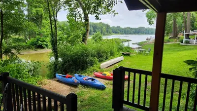 a group of kayaks sitting on the side of a river at River Log Cabins in Waterville