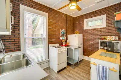 a kitchen with white appliances and a brick wall at Quaint Mt Vernon Cottage Near Historic Dtwn! in Mount Vernon