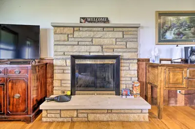 a living room with a stone fireplace with a wooden table at McArthur Cabin Peaceful Getaway on Farm! in McArthur