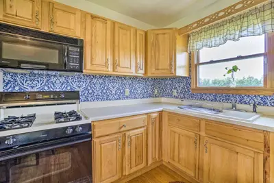 a kitchen with wooden cabinets and a stove and a window at McArthur Cabin Peaceful Getaway on Farm! in McArthur