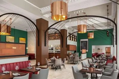 a dining room with tables and chairs and chandeliers at Hotel Ardent Dayton Downtown, Tapestry Collection By Hilton in Dayton