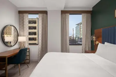 a hotel room with a bed and a desk and windows at Hotel Ardent Dayton Downtown, Tapestry Collection By Hilton in Dayton