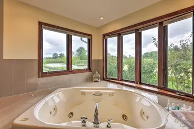 a large bath tub in a bathroom with windows at Peaceful Lebanon FarmhouseandRanch with Pool! in Lebanon