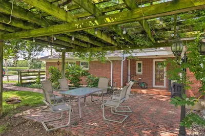 a patio with a table and chairs under a pergola at Peaceful Lebanon FarmhouseandRanch with Pool! in Lebanon
