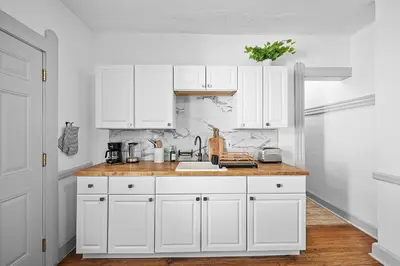 a white kitchen with white cabinets and a sink at Center of Little Italy #1 in Cleveland