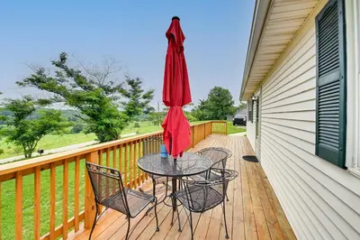 a patio with a table and chairs and an umbrella at Welcoming Kentucky Home with Sprawling Views! in Corinth