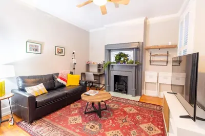 a living room with a black leather couch and a fireplace at Walkable And Cozy German Village Hauspets Ok in Columbus