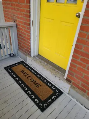 a welcome mat in front of a yellow door at Walkable And Cozy German Village Hauspets Ok in Columbus