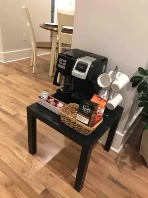 a table with a coffee maker and a basket on it at Spacious 1 bed 1 bath Downtown OTR condo minutes walk to the Reds Bengals stadium & more! in Cincinnati