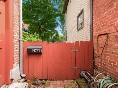 a red fence with a sign on it next to a house at Cute German Village LilHausCity ParkPetsOK in Columbus