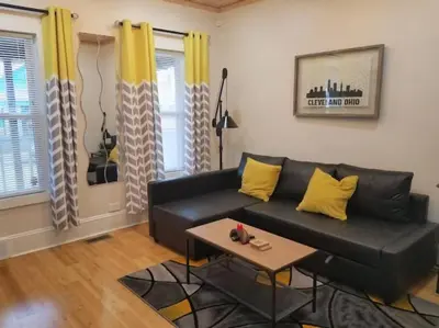 a living room with a black couch and yellow pillows at Super Close to Hot Spots in Ohio City, Cleveland in Cleveland