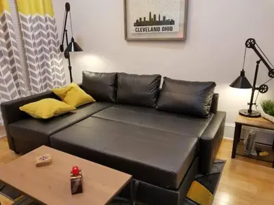 a black leather couch in a living room with a table at Super Close to Hot Spots in Ohio City, Cleveland in Cleveland