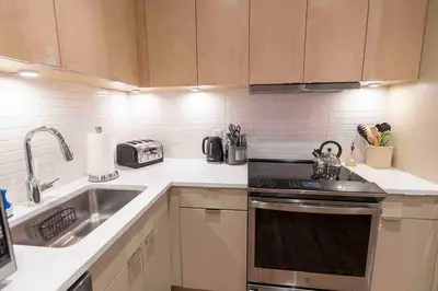 a kitchen with a sink and a stove top oven at Spacious 2 bed 2 bath Downtown OTR condo minutes walk to the Reds Bengals stadium & more! in Cincinnati
