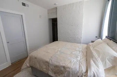 a bedroom with a bed and a white wall at Spacious 2 bed 2 bath Downtown OTR condo minutes walk to the Reds Bengals stadium & more! in Cincinnati