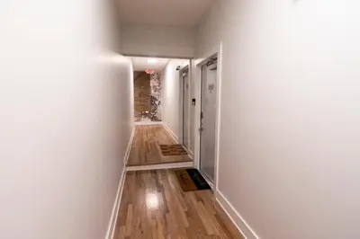 a hallway with white walls and wood floors at Spacious 2 bed 2 bath Downtown OTR condo minutes walk to the Reds Bengals stadium & more! in Cincinnati