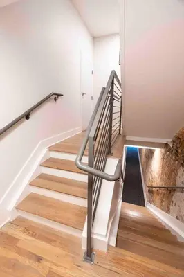 a staircase with a metal hand rail and wooden floors at Spacious 2 bed 2 bath Downtown OTR condo minutes walk to the Reds Bengals stadium & more! in Cincinnati