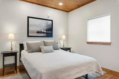 a white bedroom with a bed and two tables at Hickory Suite - Main Street Lodge in Berlin in Berlin
