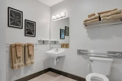a white bathroom with a toilet and a sink at Barnwood Suite - Main Street Lodge in Berlin in Berlin