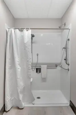 a bathroom with a shower with a white shower curtain at Barnwood Suite - Main Street Lodge in Berlin in Berlin