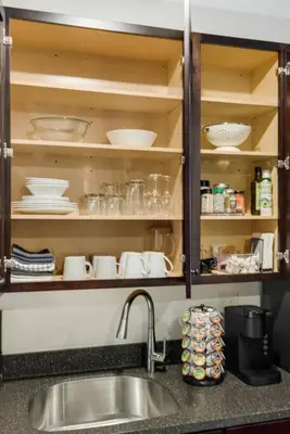 a kitchen counter with a sink and shelves with dishes at Maple Suite - Main Street Lodge in Berlin in Berlin