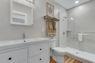 a white bathroom with a toilet and a shower at Sycamore Suite - Main Street Lodge in Berlin in Berlin