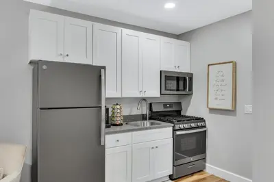a kitchen with white cabinets and a stainless steel refrigerator at Sycamore Suite - Main Street Lodge in Berlin in Berlin
