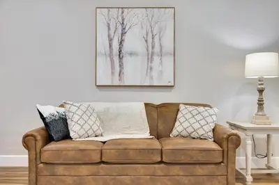 a couch in a living room with a painting on the wall at Sycamore Suite - Main Street Lodge in Berlin in Berlin