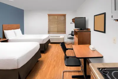 a hotel room with two beds and a desk and a television at Extended Stay America Select Suites - Cleveland - Airport in Cleveland