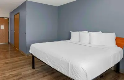 a large white bed in a room with a blue wall at Extended Stay America Select Suites - Cleveland - Airport in Cleveland