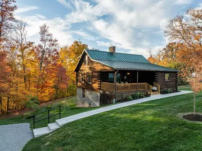 a log cabin in the woods with a green roof at Maple Leaf Cabin in Millersburg