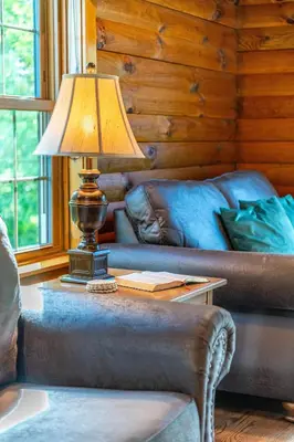 a lamp on a table in a living room with a couch at Maple Leaf Cabin in Millersburg