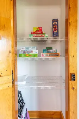 a closet with white shelves and books at Maple Leaf Cabin in Millersburg