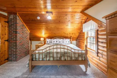 a bedroom with a bed in a wooden room at Maple Leaf Cabin in Millersburg