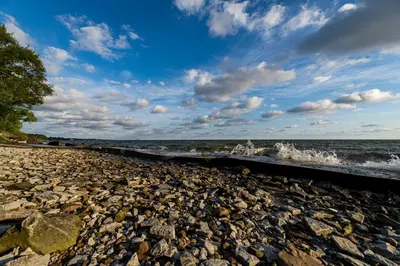 a rocky beach with waves crashing on the shore at Cozy Lakefront Cottage in Huron