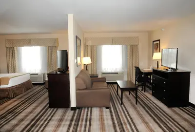 a hotel room with a bed and a couch and a desk at Holiday Inn Express & Suites Cambridge by IHG in Cambridge