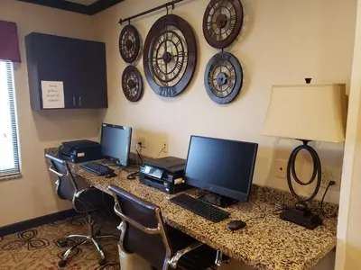 a desk with two monitors and clocks on the wall at Holiday Inn Express & Suites Cambridge by IHG in Cambridge