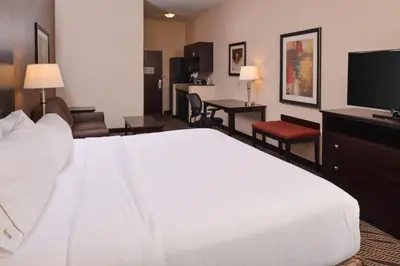 a hotel room with a white bed and a flat screen tv at Holiday Inn Express & Suites Washington - Meadow Lands by IHG in Washington