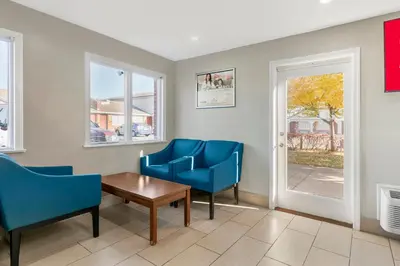 a living room with two blue chairs and a table at HomeTowne Studios by Red Roof Georgetown, KY in Georgetown