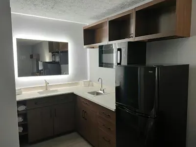 a kitchen with a black refrigerator and two sinks at HomeTowne Studios by Red Roof Georgetown, KY in Georgetown