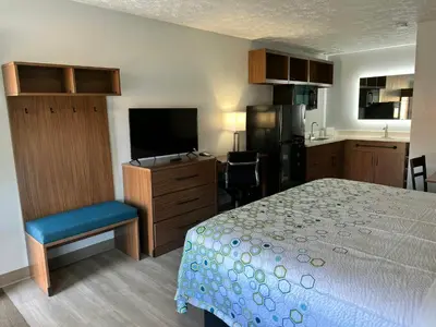 a bedroom with a bed and a tv and a kitchen at HomeTowne Studios by Red Roof Georgetown, KY in Georgetown