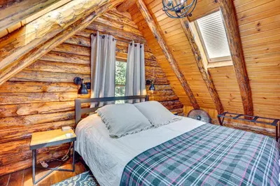 a bedroom with a bed in a log cabin at Peaceful Creekside North Studio with Fire Pit in Holmesville