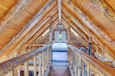 a bedroom in a wooden house with a bed in it at Peaceful Creekside North Studio with Fire Pit in Holmesville