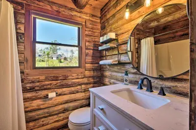 a bathroom with wooden walls and a sink and a mirror at Peaceful Creekside North Studio with Fire Pit in Holmesville
