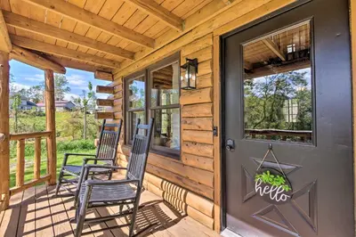 two chairs on the front porch of a log cabin at Peaceful Creekside North Studio with Fire Pit in Holmesville
