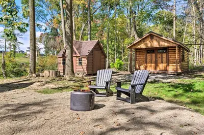 two chairs sitting in front of a log cabin at Peaceful Creekside North Studio with Fire Pit in Holmesville
