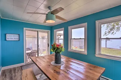 a dining room with a wooden table and windows at Lakefront Cottage with Fishing and Private Yard! in Port Clinton