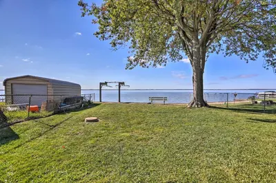 a park with a tree and a bench and the water at Lakefront Cottage with Fishing and Private Yard! in Port Clinton