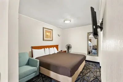 a hotel room with a bed and a blue chair at Americas Best Value Inn-Celina in Celina