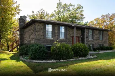 a small brick house with a yard at Sleeps 12, Wooded Lot, Near Ark, Great for Family in Williamstown