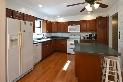 a kitchen with wooden cabinets and a white refrigerator at Sleeps 12, Wooded Lot, Near Ark, Great for Family in Williamstown